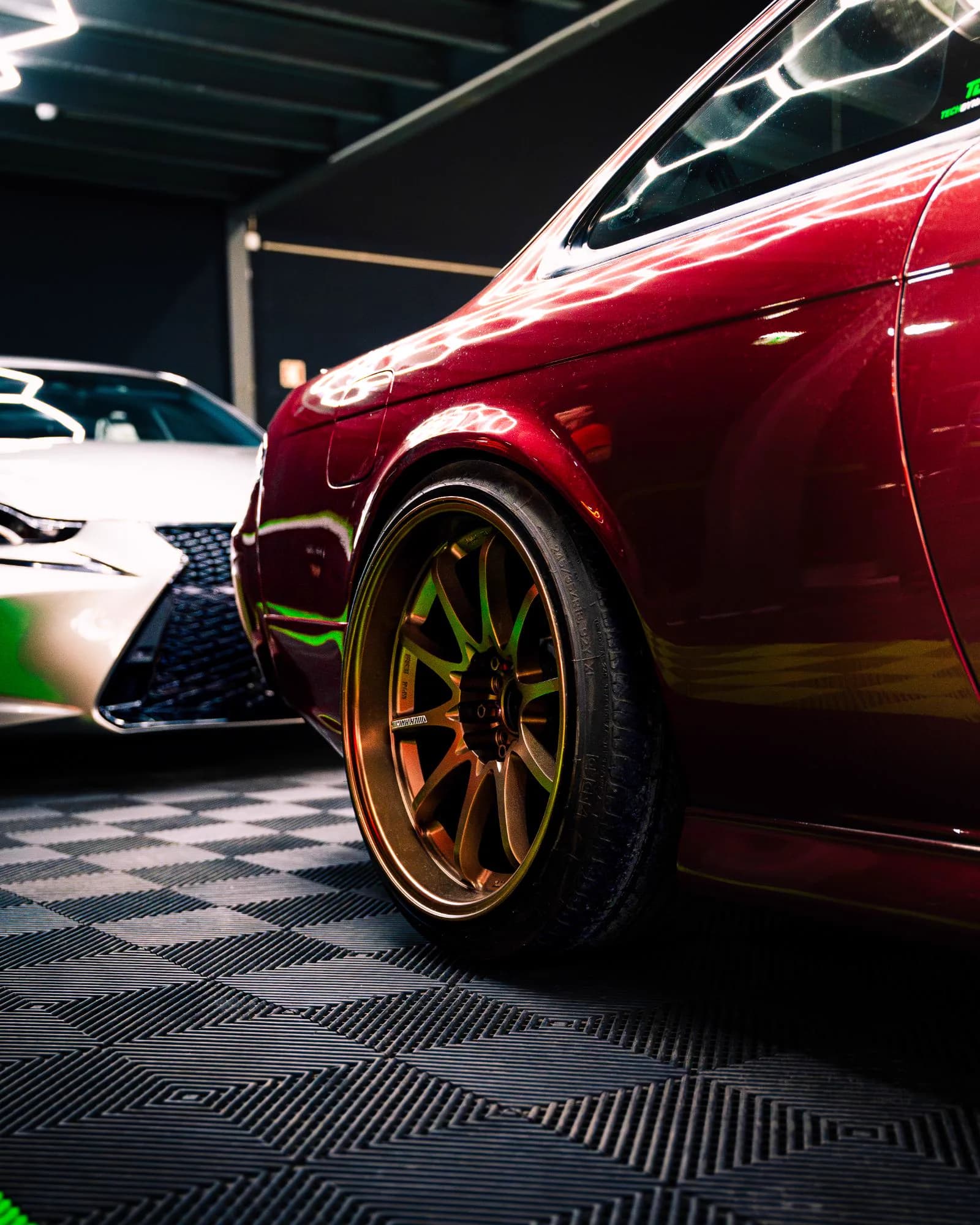 Pormenor da jante bronze de um Nissan Silvia S14 vermelho, com um Lexus IS ao fundo