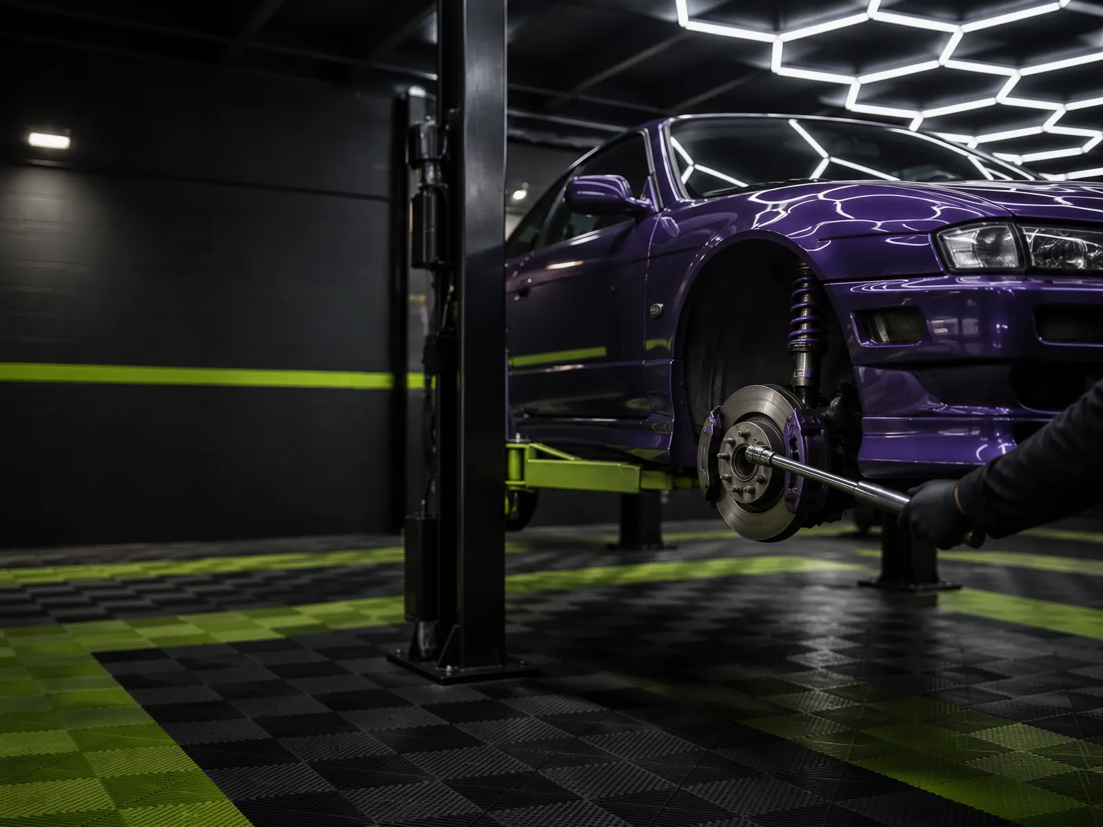 Nissan Silvia S14 roxo no elevador, sem a roda da frente, com o mecânico a apertar o cubo junto ao disco de travão